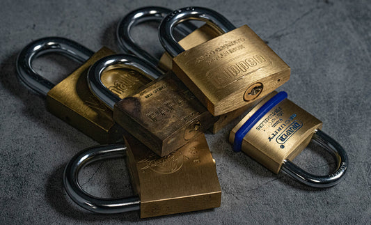 Close-up of multiple brass padlocks on a dark surface, symbolizing security.